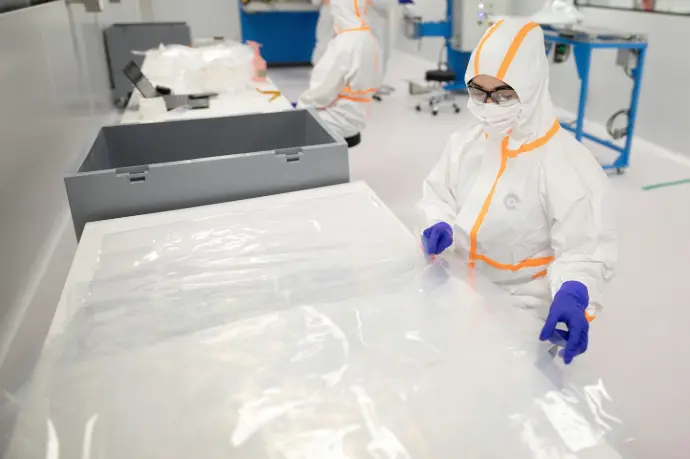 Workers in protective suits inside a cleanroom.